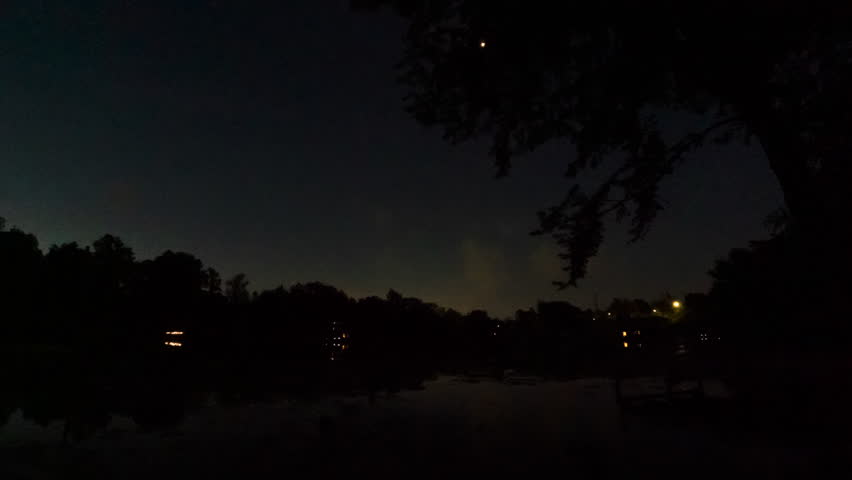 Timelapse the sun rises over a small dock on a still lake in central Michigan.  The sky is mostly clear.