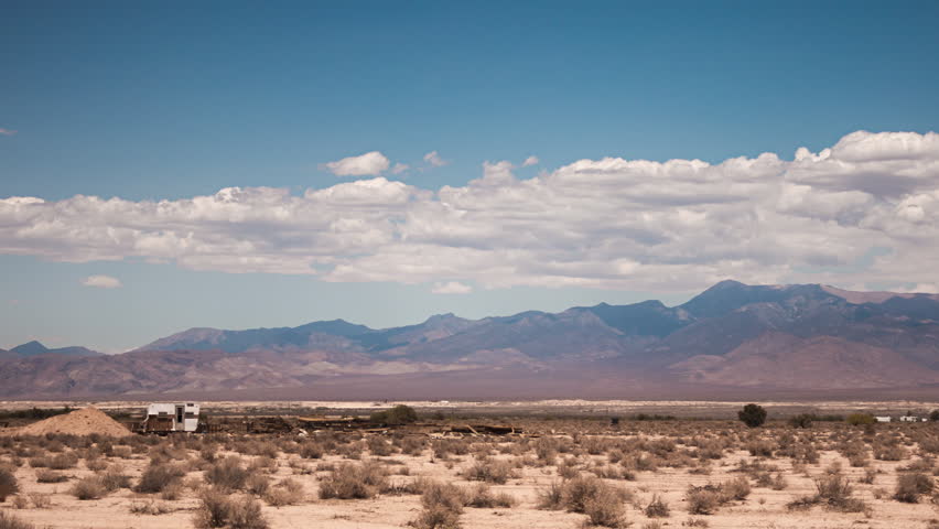 Timelapse Slider shot of clouds forming and evaporating over mountains in the Mojave Desert, California.  A camper can be seen in the distance.