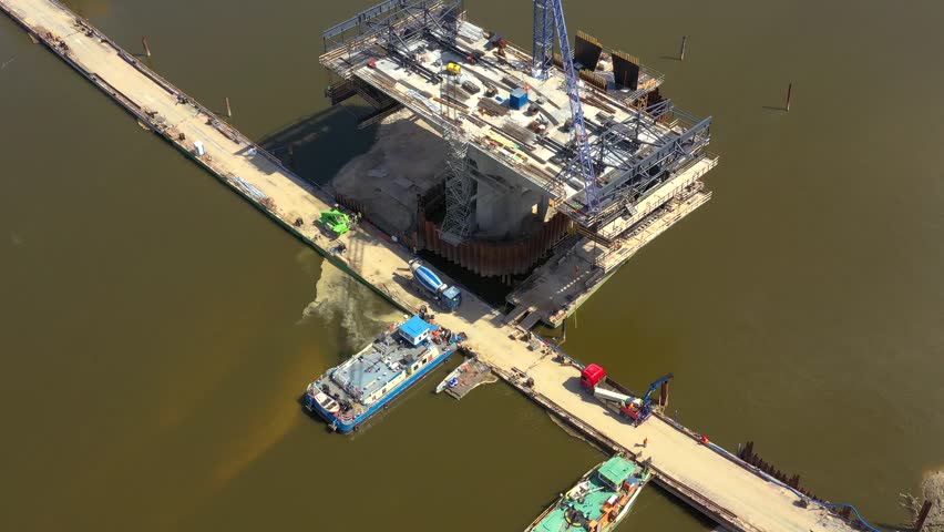 Construction of a new bridge over the river. Tower cranes over the bridge across. Excavators and loaders working on bridges and roads. Warsaw. Poland
