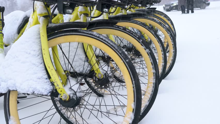 Bicycles stand on the snow-covered street in winter.