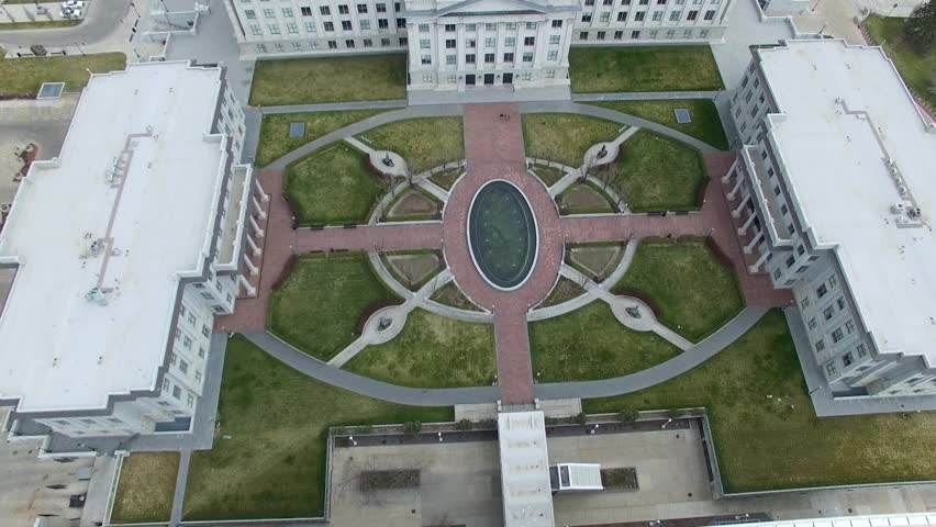 Top down aerial view of the Utah City Capitol courtyard and building, tilt up to reveal downtown Salt Lake City.