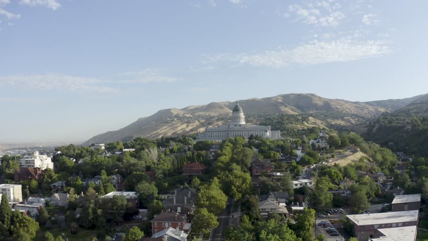 Drone shot on a warm summer day pushing in towards the Utah State Capitol building.