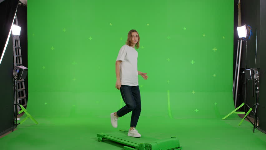 Woman with beautiful smile doing presentation and gesturing on green screen . Attractive girl makes gestures with her hands pointing to the space on the background . Chroma key