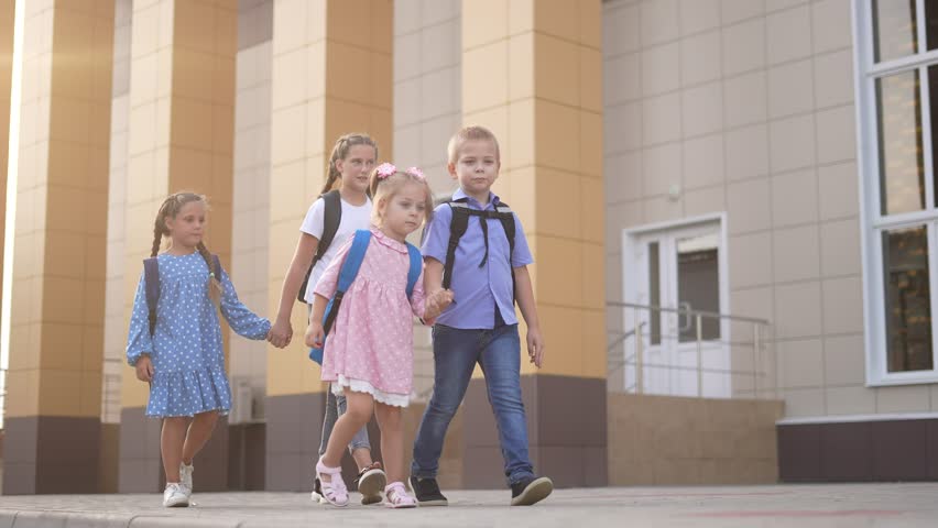 back to school. a group of schoolchildren with backpacks walk next to the school. education kids concept. schoolboy and schoolgirl going to school. lifestyle a group of children walking
