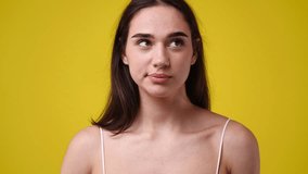 4k slow motion video of girl with cunning facial expression on yellow background.