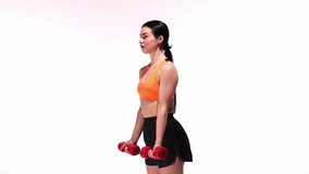 Young sportive girl training with dumbbells over white studio background. Hands training, lifting weights. Modern sport, action, motion, youth concept. Fitness, hobby, healthy lifestyle