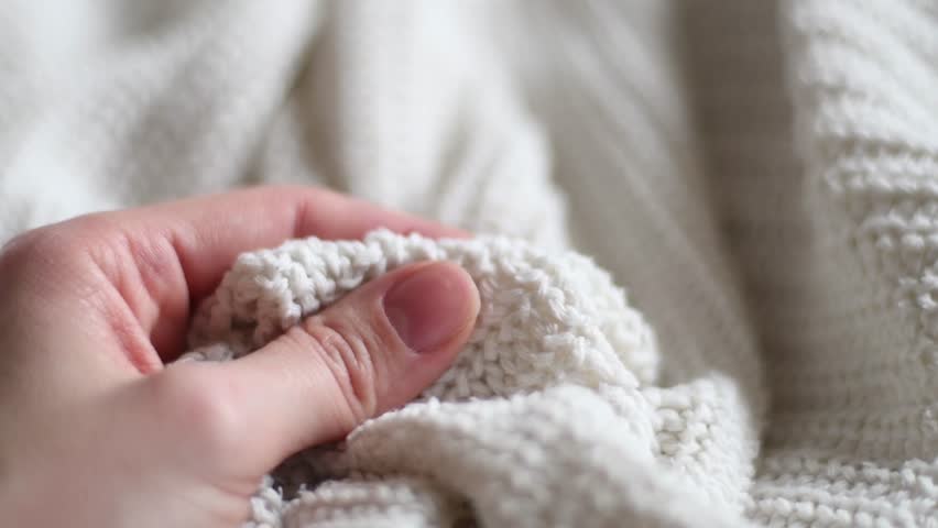 Hand stroking over the surface white knitted wool cloth or warm fluffy sweater. Handcraft knitting woolen fabric. Clothing industry concept. Woman enjoys the soft pleasant texture of the fabric. Royalty-Free Stock Footage #1098449923