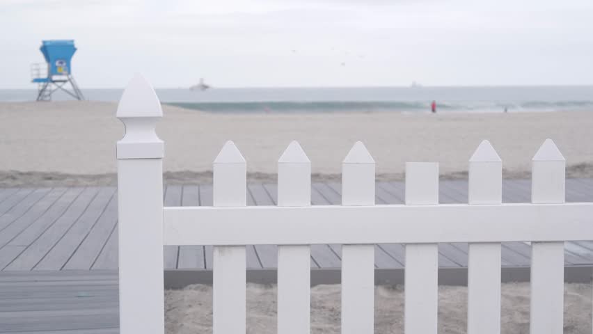 Lifeguard stand or life guard tower hut, surfing safety on California beach, USA. Rescue station, coast lifesavers wachtower or house, Coronado ocean beach, San Diego shore. White wooden picket fence.