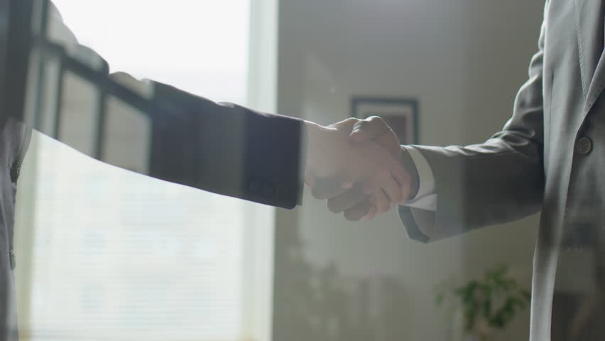 View through glass wall of multiethnic business people in formalwear shaking hands in office | Shutterstock HD Video #1098457249