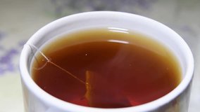 Hot tea brewed with tea bag in a black steaming cup. Close up stock video