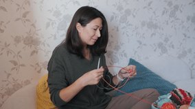Close-up video of woman knitting something small. Anti-stress hobby. Tranquil leisure at home. Handicraft. Online lessons for amateurs on laptop.