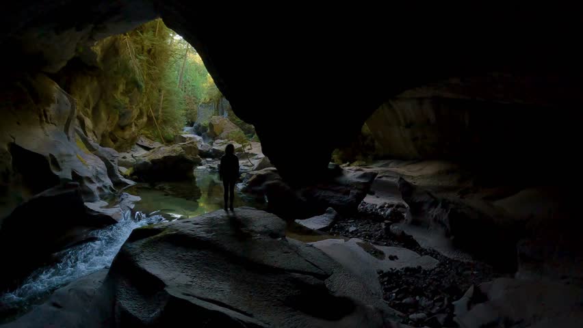 Adventurous woman standing inside a cave. Adventure Travel. Little Huson Caves Park, Vancouver Island, British Columbia, Canada. Slow Motion Cinematic