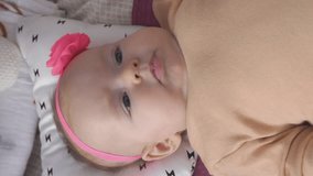 Vertical video. Cute happy baby girl lying on changing table, smiling to her mother. Family memories and happy childhood concept