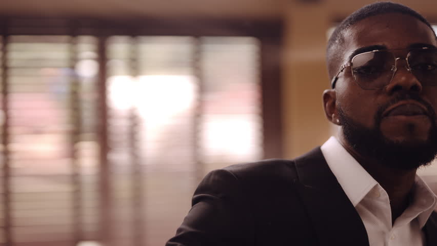 A medium shot of a man looking straight at the camera and fixing his suit