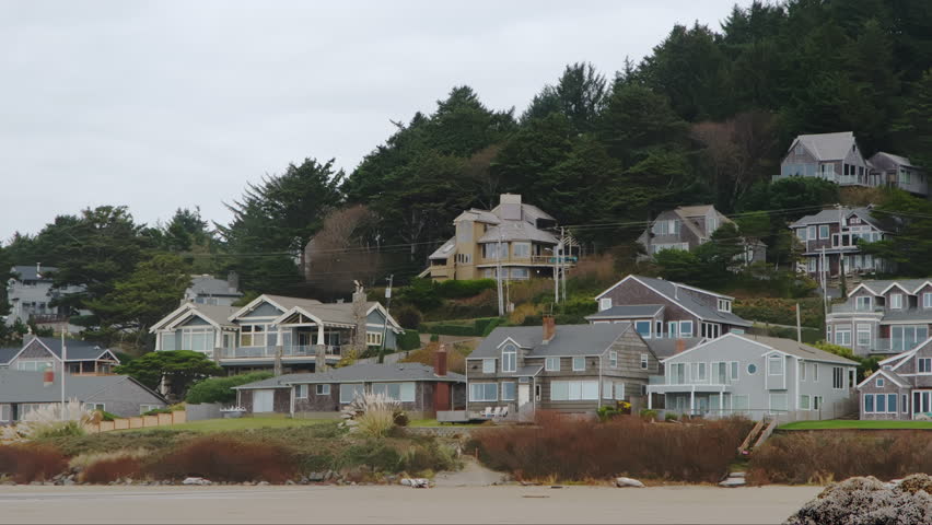Wide footage of beach in coastal town Cannon Beach and real estate Houses, Oregon. Wide shot on cloudy day