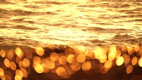 Blurred orange sea at sunset. Sun reflects and sparkles on waves with bokeh lights. Full HD slow motion video. Abstract summer natural background. Copy space for your text.