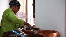 Horizontal video of a Latina woman preparing food in a rustic kitchen.