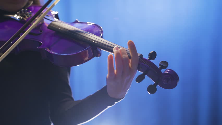 Close-up of young female musician playing violin on stage and her violin.
Close-up of woman playing violin on opera stage or music hall.
