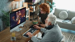 Happy grandfather and grandson at home have fun and rejoice in victory playing 3d game on computer celebrating victory and success 