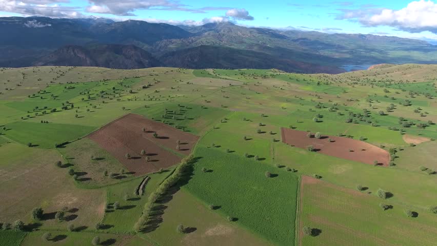 Aerial view of flat farmland on high plateau above mountains.