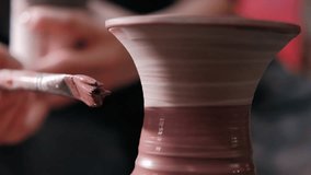 Female potter paints on rotating clay pot on the pottery wheel. Close up shot of potter making ceramic pot on pottery wheel at workshop, slow motion. Creativity and traditional crafts concept. - Powered by Shutterstock - Get 15% off with code: PIKWIZARD15