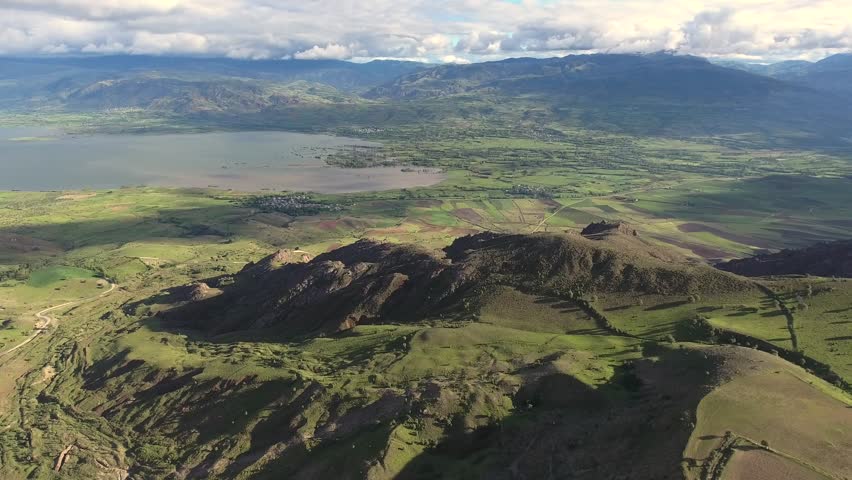 Aerial view of topographic terrestrial geography with treeless hills around the lake.