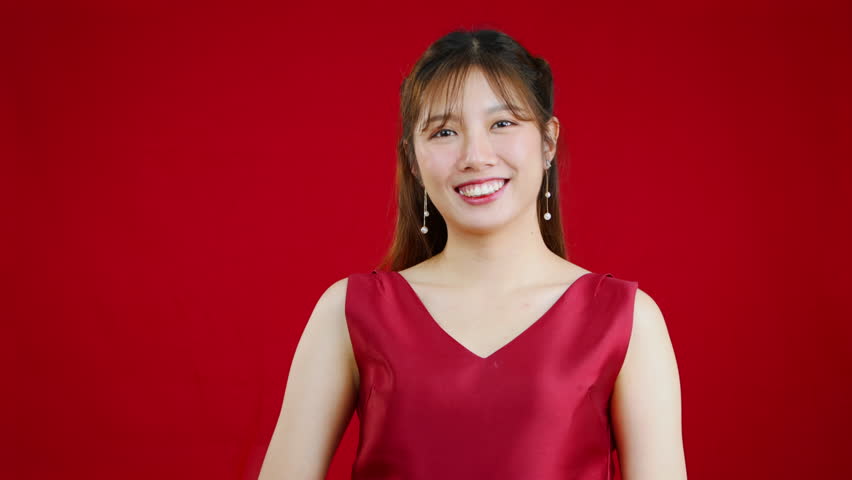 Beautiful asian woman long hair in red dress posing on red background video 4K to celebrate Chinese New Year.