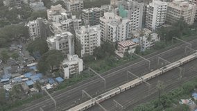 In this video, a train can be seen speeding along the tracks as it travels through the bustling cityscape of Mumbai as camera pans through the city 
