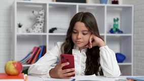 busy kid chatting using smartphone in classroom with amazed face, study