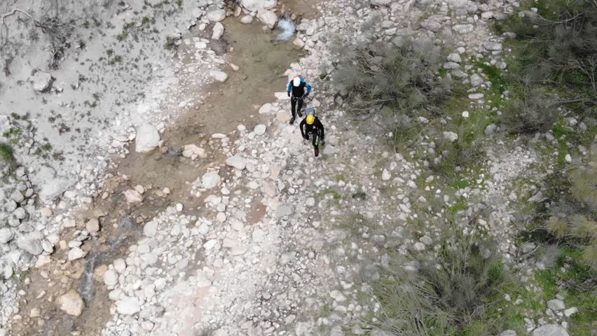Canyoners walking through the rocky river bed. Aerial view from drone.