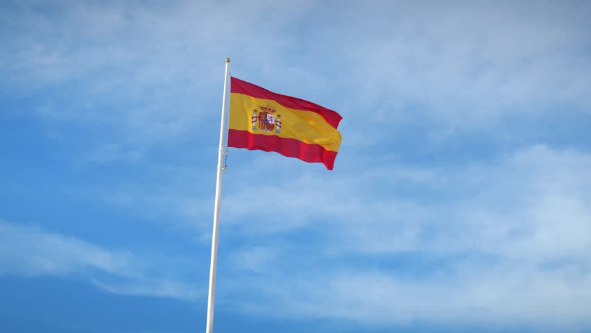 Bandera de andalucía, españa en el asta de la bandera ondeando en el viento  aislado sobre fondo de cielo azul