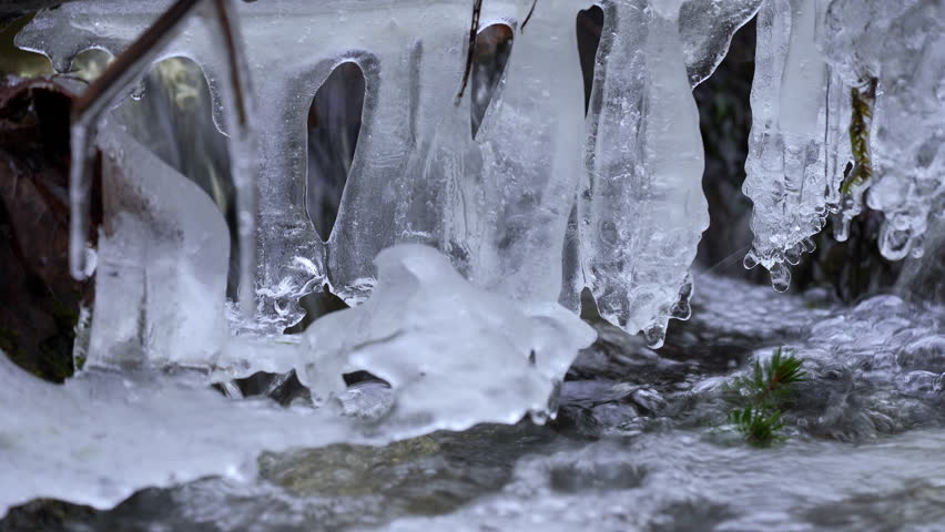 Small rapid river in winter. Melting water in spring. Falling icicles in the spring river. Winter Rapids In A Small River. High quality 4k ProRes footage