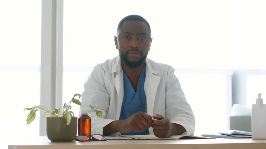 Professional online consultation. Camera pov shot of young black doctor streaming in internet, recommending vitamin pills to subscribers, sitting at office, slow motion | Shutterstock HD Video #1098528681