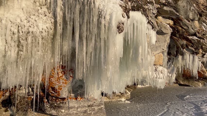 Frozen winter lake Baikal, Siberia, Russia. Ice icicles and blocks in the rocks, grottoes and caves at dawn. Natural background of cold ice. Winter abstract background. High quality 4k footage