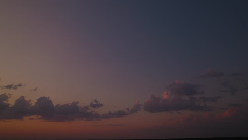 A sunset sky with a blue and golden gradient and colorful solar rays. A romantic skyscape panorama with sunlight beams during the sunrise. An aerial view of heaven with an orange glow at dusk.