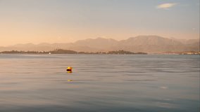 Footage, sunset over a bay in the Aegean Sea, calm sea, 4k video, selective focus on a yellow buoy. Idea for background or wallpaper