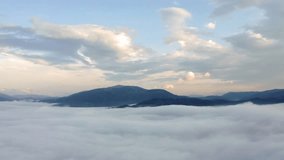 4k drone forward video (Ultra High Definition) of flying drone above the clouds. Foggy summer scene of mountain range. Stunning morning view of misty Carpathian mountains, Ukraine, Europe. 