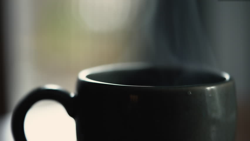 Hot cup of tea or coffee on table. Closeup of beverage mug with steam