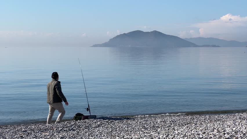 a man with a spinning rod on the seashore fishing