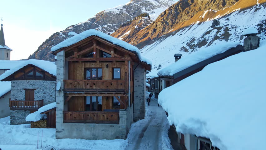 Amazing panorama of Swiss Alps covered with snow in sunlight, small tourists village at the foot of rock mountains, famous ski resort and relax complex for tourists. Beauty of winter nature in