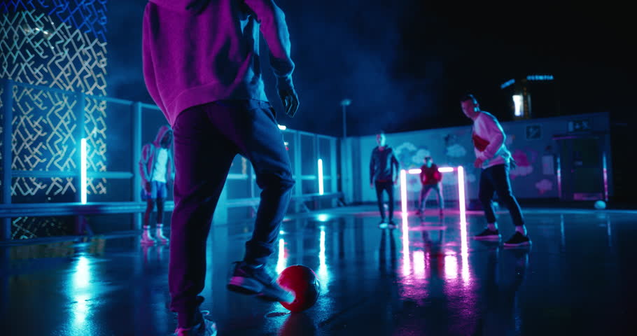 Multiethnic Diverse Friends Playing Soccer Outside on Rooftop Urban City Spot with Neon Lights After Rain. Skilful Young Man Dribbling, Passing Opponents Alone with the Ball and Scoring a Goal