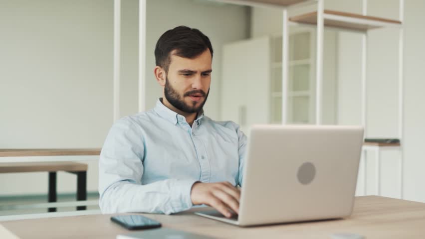 Concentrated adult guy searching in laptop while sitting at table | Shutterstock HD Video #1098554633