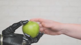 Robotic arm gives green apple to person close-up. New technologies, testing of artificial hand. - Powered by Shutterstock - Get 15% off with code: PIKWIZARD15