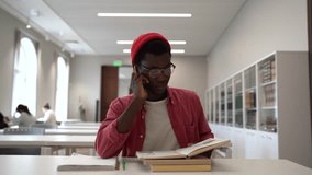 Talented young black guy scientist wearing glasses studying in library, reading book and taking notes. Focused African American male student writing research summary, sitting at desk. Education - Powered by Shutterstock - Get 15% off with code: PIKWIZARD15