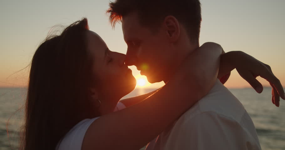 Young loving couple spend time on the beach at sunset. Man and woman embrace in sunset light standing together on the beach close-up. Travel vacation lifestyle. Royalty-Free Stock Footage #1098564207