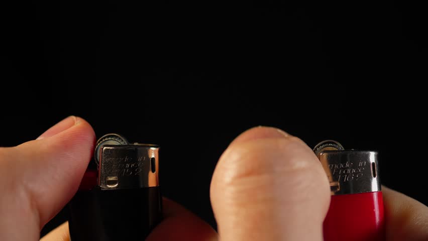 Two lighters are lit simultaneously in different parts of the frame, one on the right and the other on the left close-up | Shutterstock HD Video #1098565295