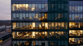 Cinematic view from a drone of the office windows of a glass skyscraper with business people working late. Panorama of a drone in the distance of the windows of a skyscraper close-up - Powered by Shutterstock - Get 15% off with code: PIKWIZARD15