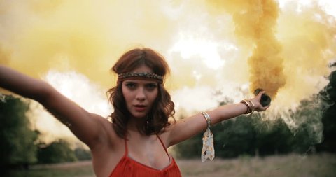 Beautful boho girl in a natural park playing and dancing with yellow smoke in Slow Motion