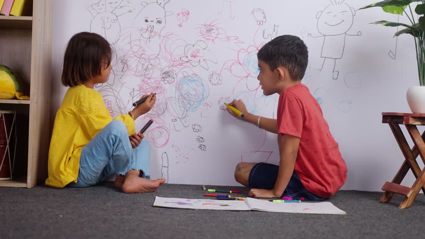 Young siblings kids drawing with crayon color on wall by looking at camera at home - concept of mischief, troublesome children and childhood lifestyles. Royalty-Free Stock Footage #1098571339