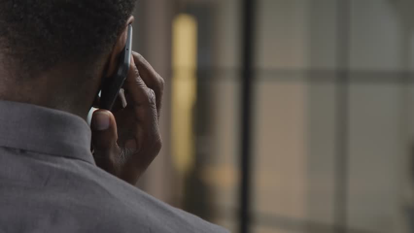 An over-the-shoulder shot of Black man's head talking on the phone with copy space. Royalty-Free Stock Footage #1098571357